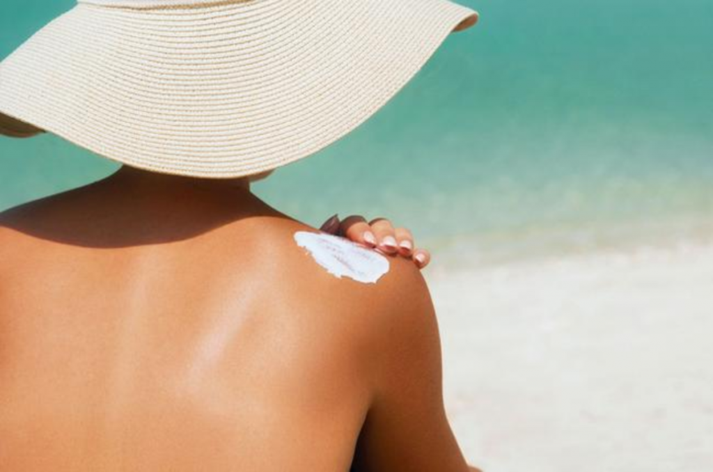 Jeune femme assise à la plage avec un chapeau contre le soleil